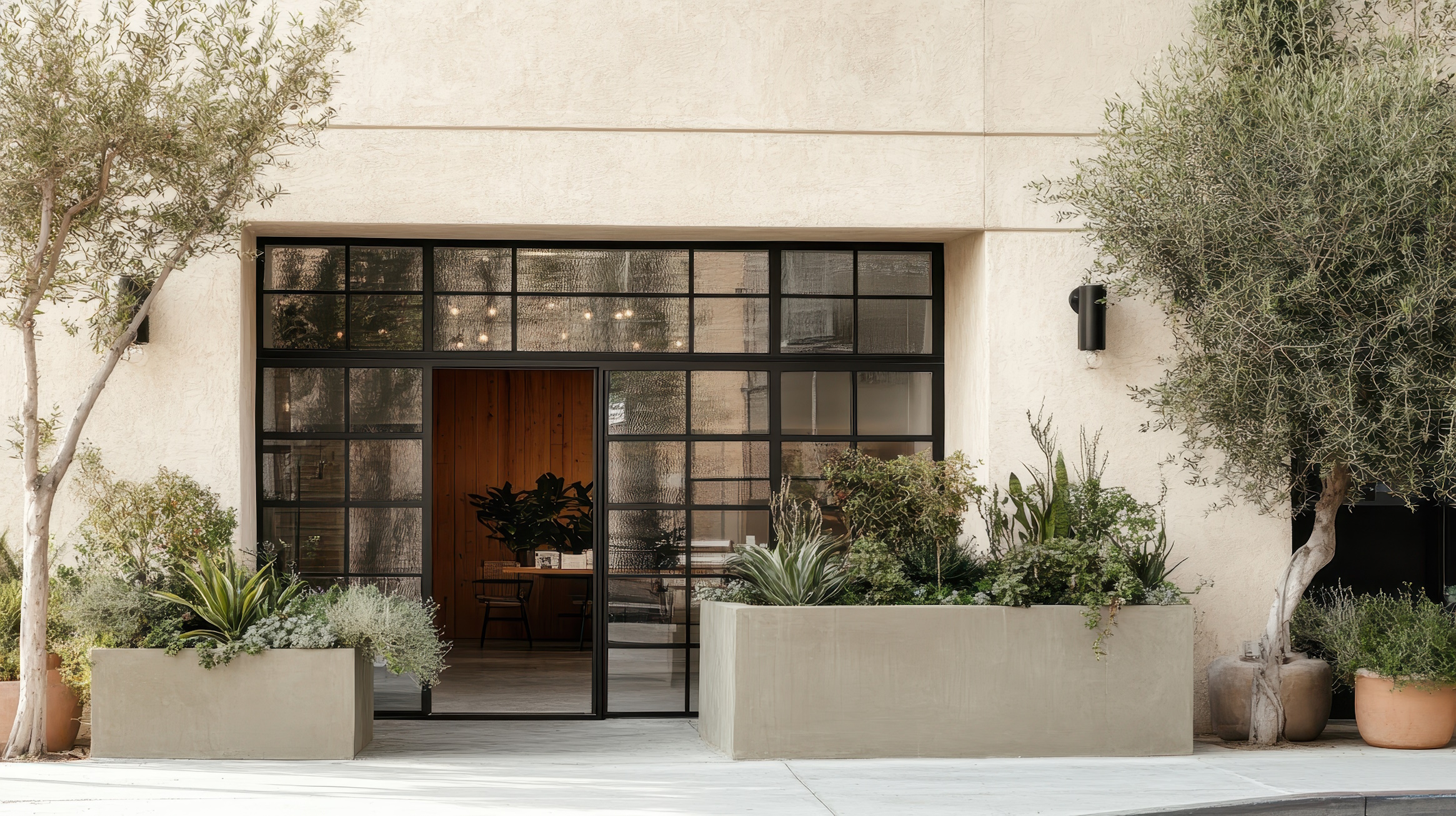 Modern building entrance with black framed glass doors and concrete planters. Use for architectural or interior design stock, showcasing stylish design.